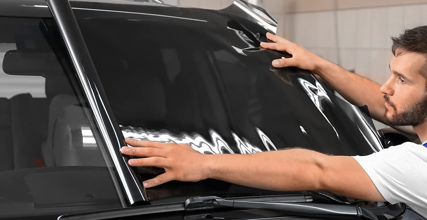 Installer fitting dark window tint film on a windshield